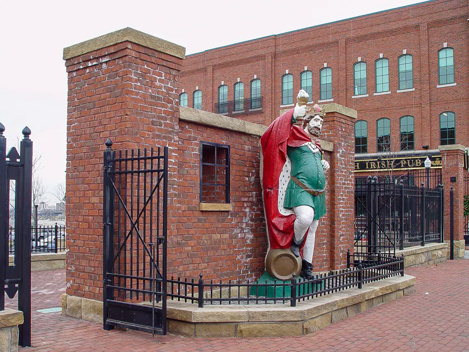 Iron gate, brick pier, stone base, public art, and Brewer's Yard sign at a commercial entry.
